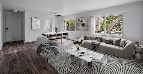 A modern living room with a grey sofa, a grey armchair, a coffee table, and a rug.