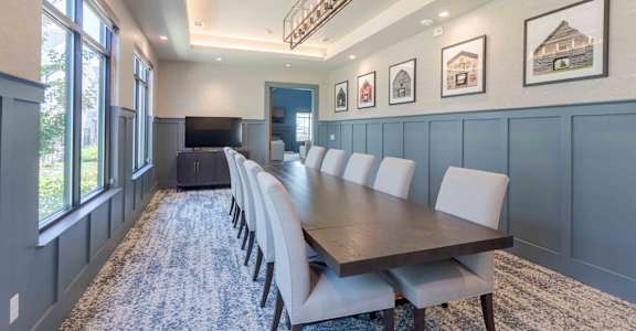 A long table with chairs is set up in a room with a blue wall.