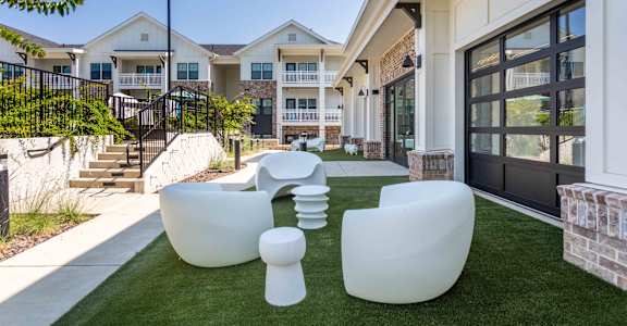 A white outdoor furniture set is placed on a green lawn.