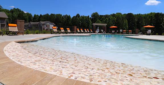 A pool surrounded by stone tiles and chairs.