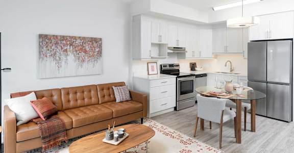 A modern kitchen with a brown leather couch and a dining table.