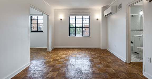 A room with wooden flooring and a window.