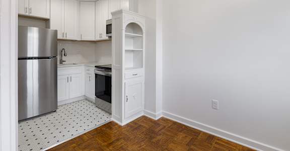 A kitchen with white cabinets and a black and white floor.