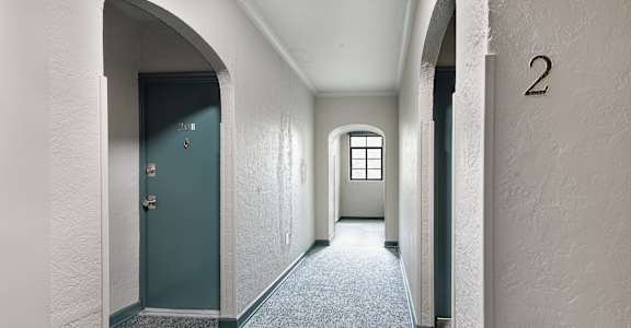 A hallway with a blue door and a window.