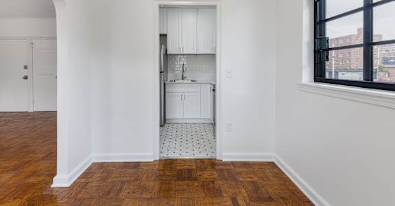 A kitchen with white cabinets and a wooden floor.