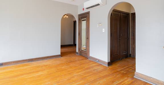 A room with a wooden floor and a wall-mounted air conditioner.