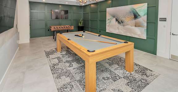 Recreational clubroom with pool and foosball tables, a chandelier, TV, green walls, and rug