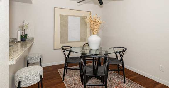 a dining room with a glass table and chairs and a ceiling fan at Rocklin Manor  Apartments, Rocklin  , CA 95677