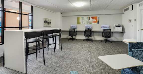 A room with a white reception desk and several chairs.