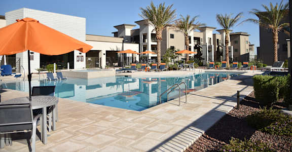 A pool area with a table and chairs and umbrellas.