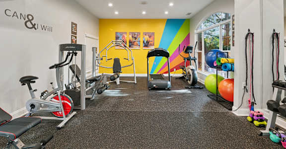A gym with a variety of equipment including treadmills, weights, and exercise machines.