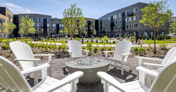 an outdoor patio with white chairs and a fire pit