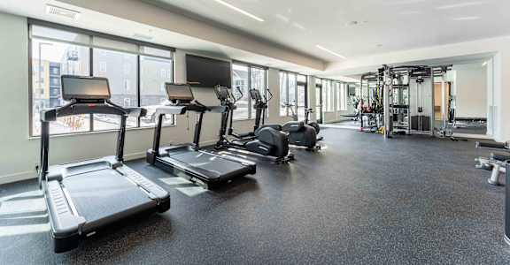 a gym with cardio equipment and windows in a building