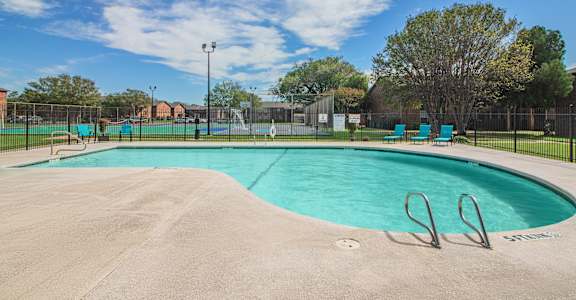 A large swimming pool surrounded by a fence with a clear blue sky above.