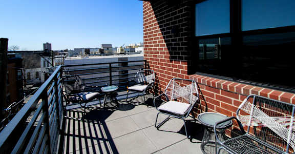 A balcony with a table and chairs overlooking a cityscape at The Nines Apartment Homes Apartments, Allentown, PA, 18101
