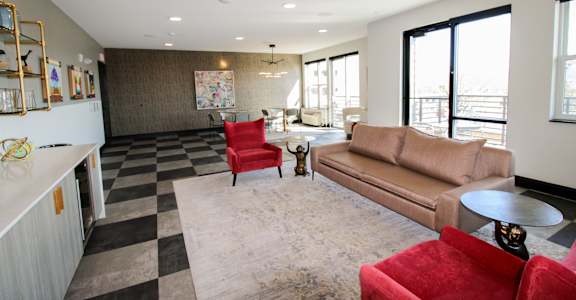 A living room with a red chair and a brown couch at The Nines Apartment Homes Apartments, Allentown, PA, 18101