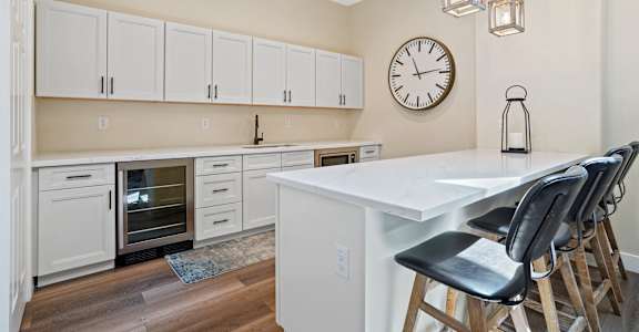 A kitchen with a white table and black chairs.