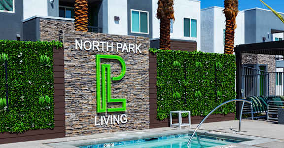 A pool in front of a wall with North Park Living written on it.