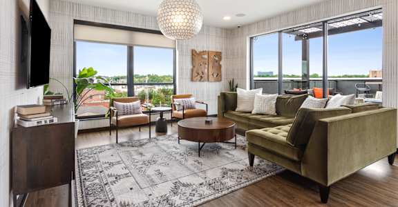 A living room with a green couch and a large window.