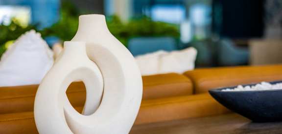 A white ceramic vase with a spiral design sits on a wooden table.