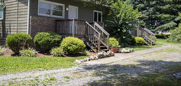 the front of a house with a porch and a sidewalk
