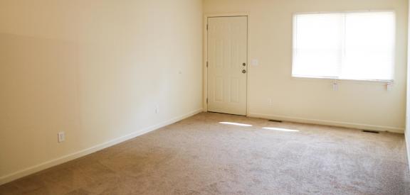 an empty living room with a door and a window