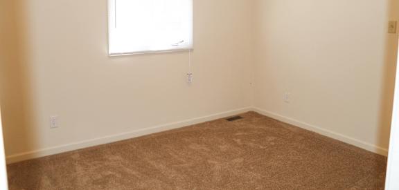 an empty room with a window and a carpet