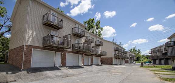an empty street in front of an apartment building with white doors and balconies