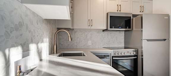 A modern kitchen with a white marble countertop and stainless steel appliances.