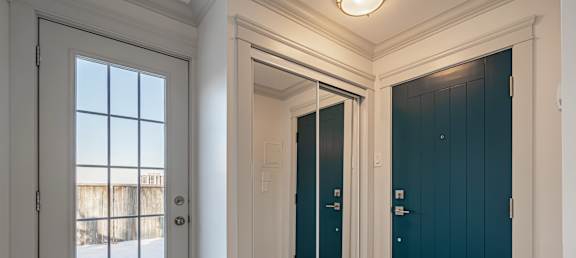 A white door with a window is on the left and a dark blue door is on the right.