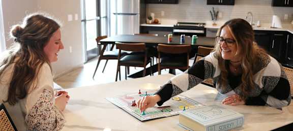 Two women sitting at a table with a book titled "Sorry" in front of them.