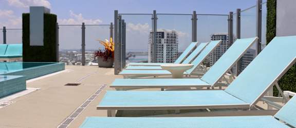 a row of blue lounge chairs on a rooftop overlooking the city