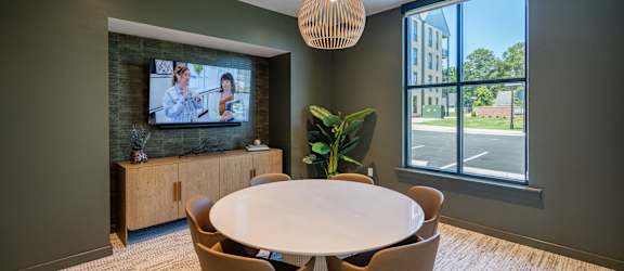 A conference room with a large table, chairs, and a television on the wall.