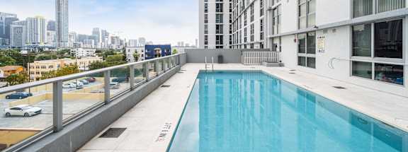 a swimming pool on the balcony of a building with a city in the background