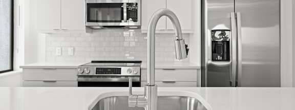 A modern kitchen with a stainless steel refrigerator and a sink.