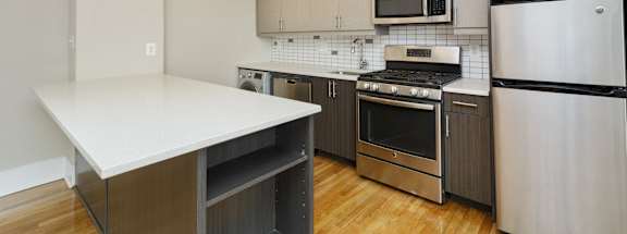 a kitchen with white countertops and stainless steel appliances