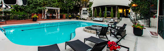 A pool with a black table and chairs in front of a building.