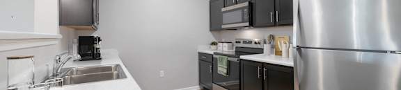 A modern kitchen with a stainless steel refrigerator and black cabinets.