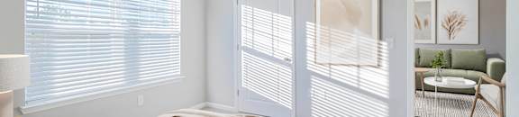 A bedroom with a large bed and a window with blinds.