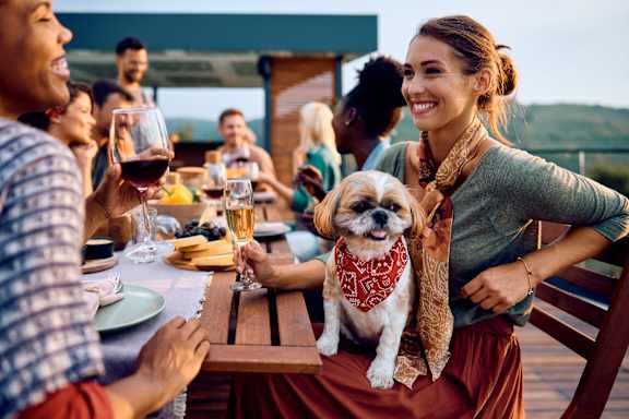 A woman with a dog at a dinner table with people.