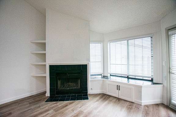 A white room with a fireplace and wooden floors.