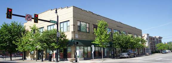 A street view of a building with cars parked in front.