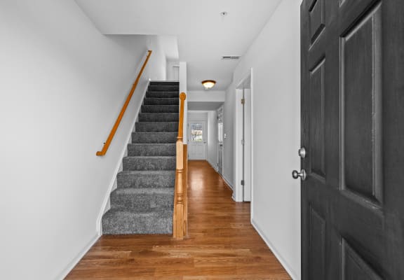 a staircase in a home with a black door and wood floors