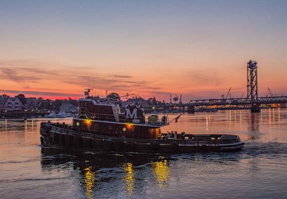 a barge on the water with a sunset in the background