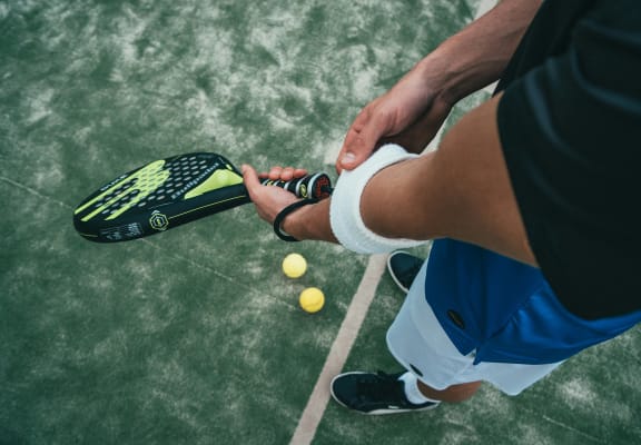 a man holding a tennis racket and two balls on a court