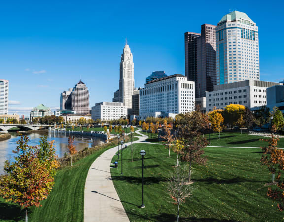 a park with a path and trees in front of the columbus skyline at Preston Centre, Columbus, 43215