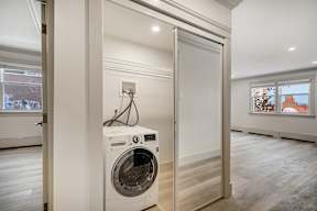A white washing machine is in a small room with a door open.