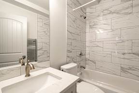 A white bathroom with a marble tile wall.