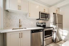 A kitchen with a stove, oven, refrigerator, and sink.
