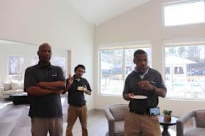Three men standing in a room with one holding a plate.